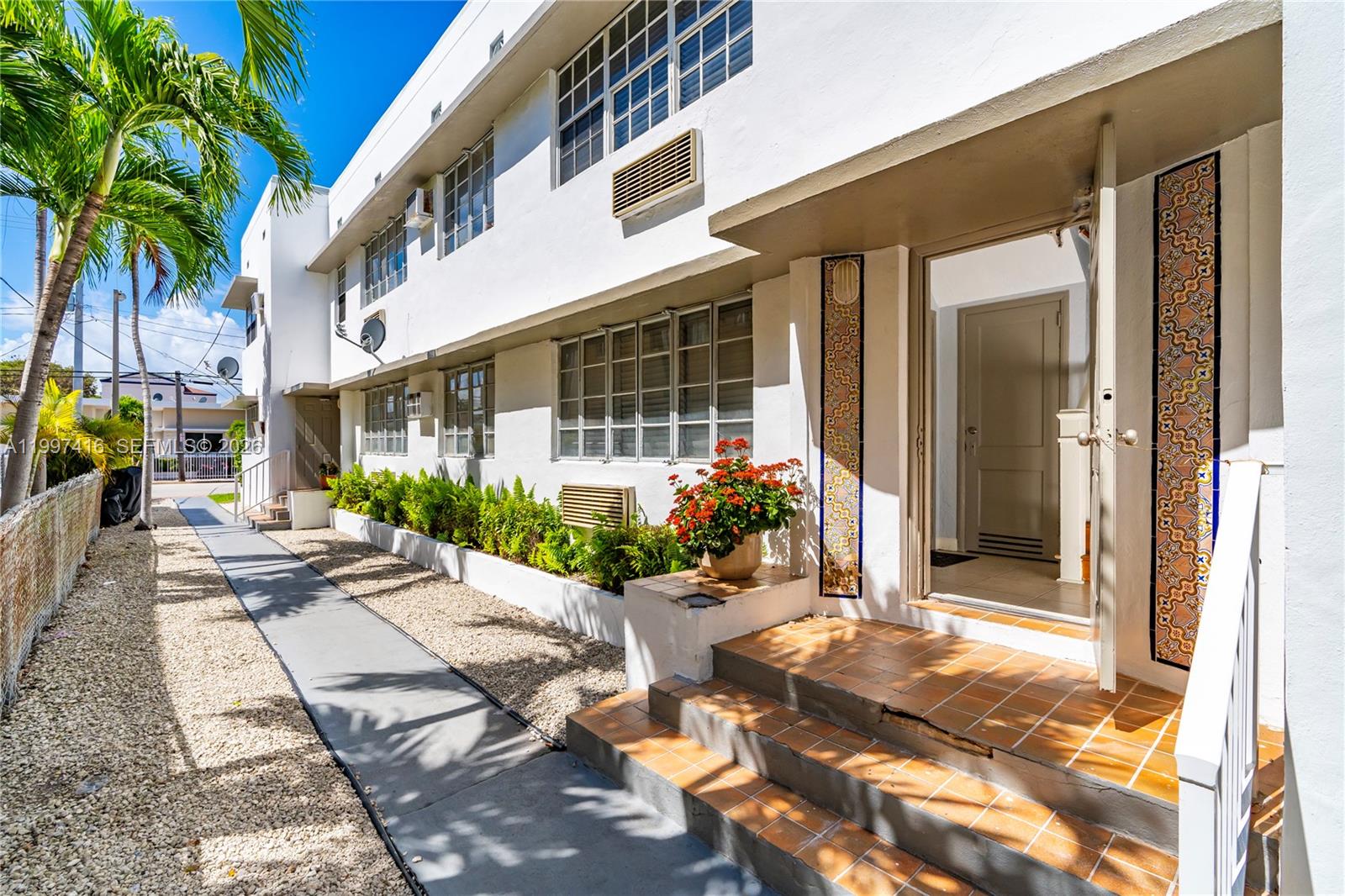 The exterior of a white two-story apartment building features a tiled entrance and walkway — 7635 Dickens Ave, Miami Beach FL 33141, MIAMI BEACH, FL