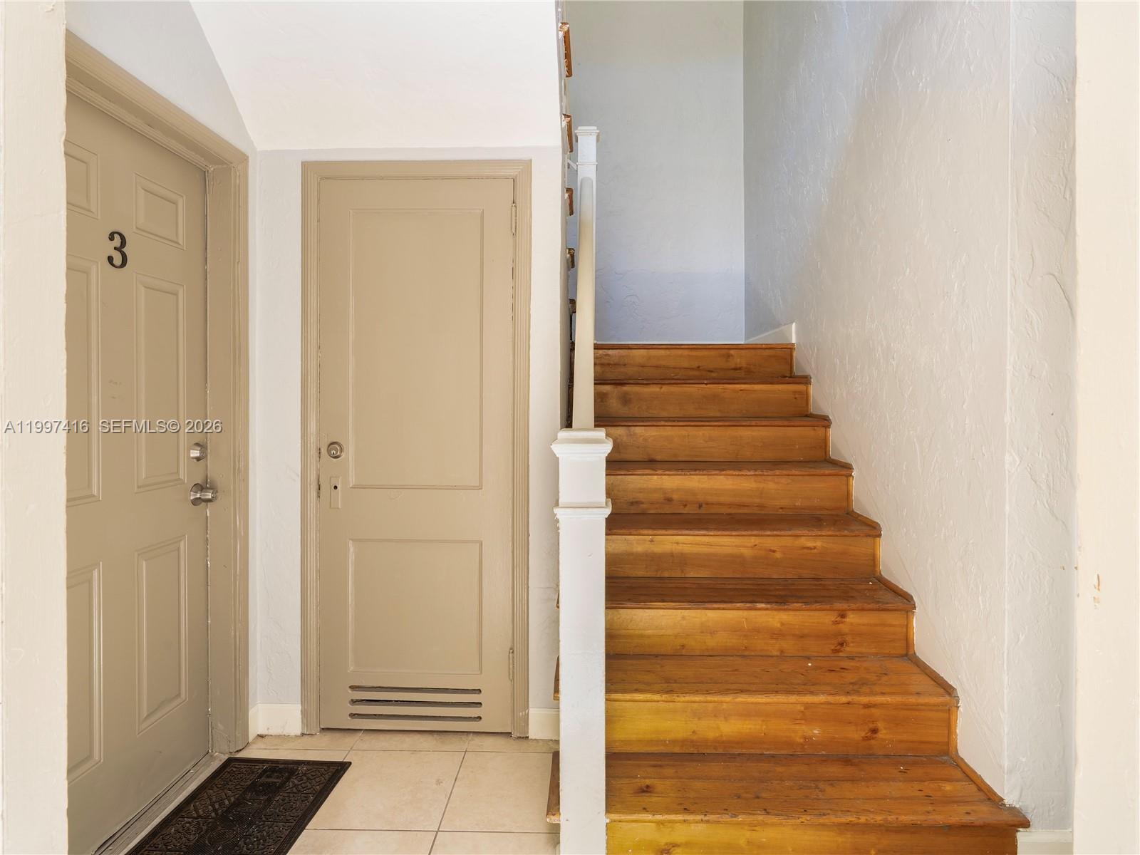 A beige door labeled 3 stands next to a wooden staircase with white railings — 7635 Dickens Ave, Miami Beach FL 33141, MIAMI BEACH, FL