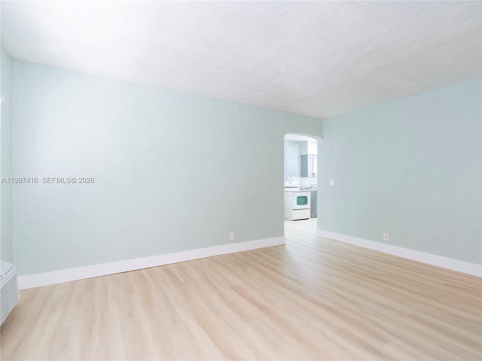 An empty room with light blue walls, white trim, and light wood-look flooring — 7635 Dickens Ave, Miami Beach FL 33141, MIAMI BEACH, FL