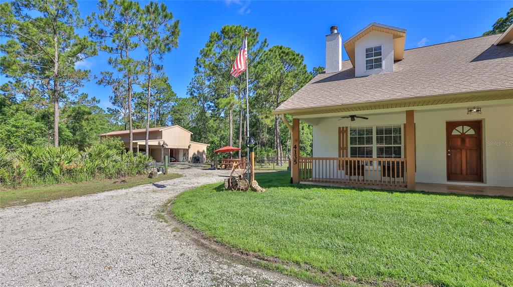 A house with a front porch and a detached garage sits on a gravel driveway — 4135 QUAIL RANCH ROAD, NEW SMYRNA BEACH, FL