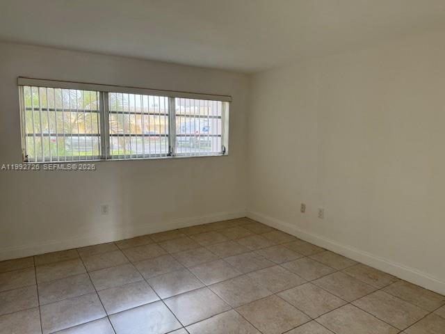 An empty room features beige tile flooring, white walls, and a window with security bars — 7350 SW 82nd St # C125, Miami FL 33143, MIAMI, FL