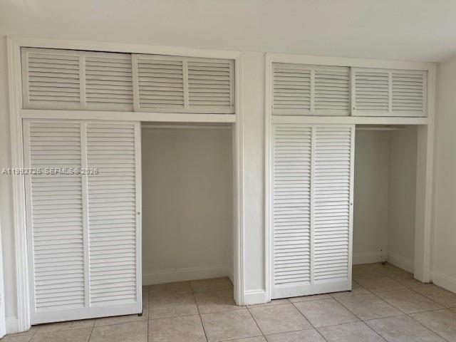 Two white louvered closet units with overhead storage compartments stand against a tiled wall — 7350 SW 82nd St # C125, Miami FL 33143, MIAMI, FL