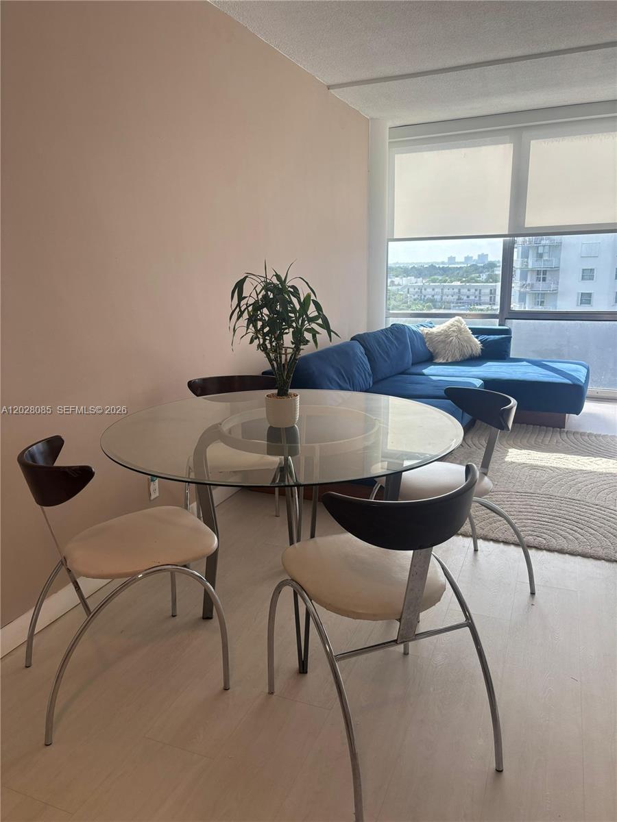 A dining area with a glass table and chairs sits next to a blue sectional sofa — 900 Bay Dr # 811, Miami Beach FL 33141, MIAMI BEACH, FL