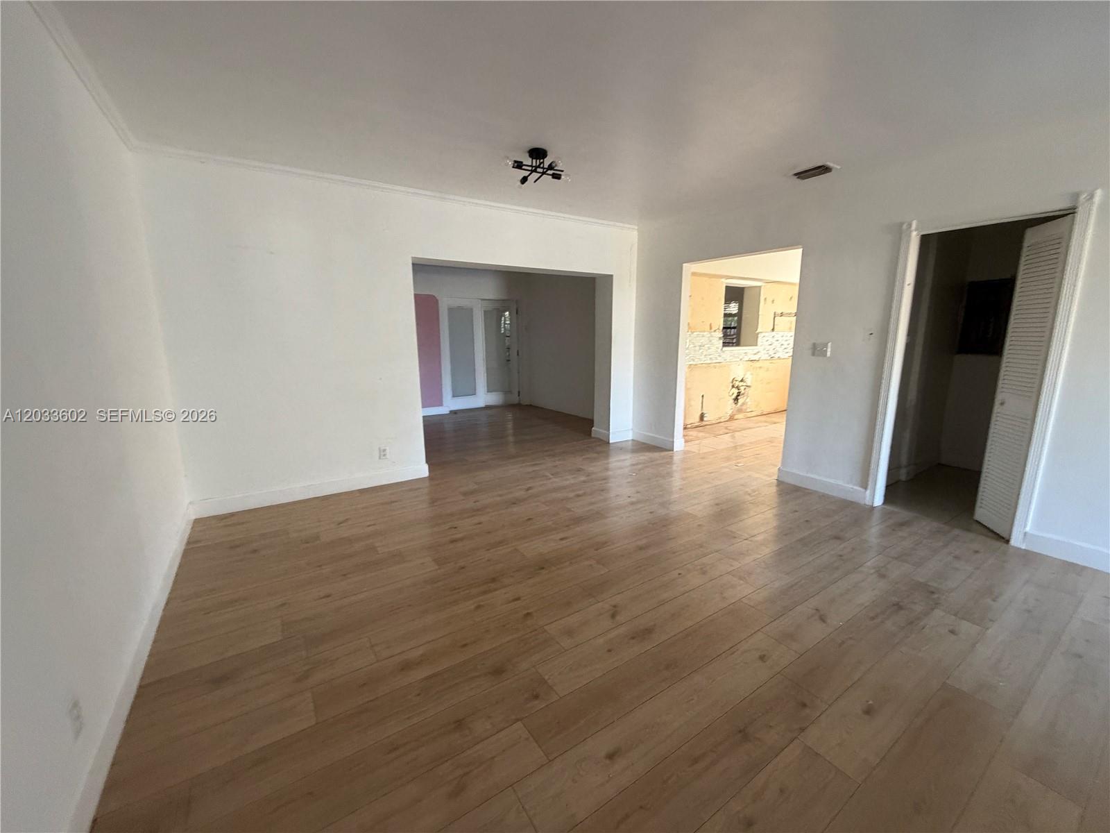 An empty room with light wood-look flooring and two doorways leading to other spaces — 1080 NE 83rd St, Miami FL 33138, MIAMI, FL