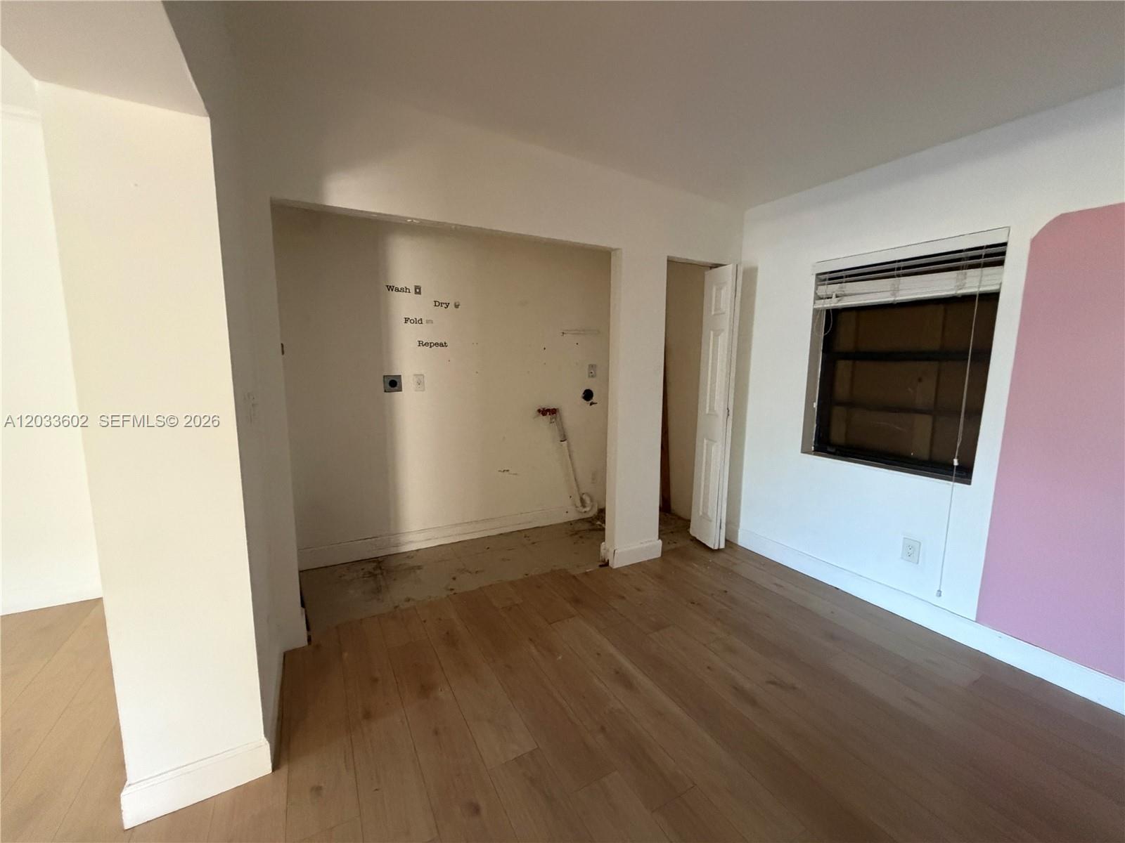 An interior room features light wood flooring, a laundry alcove with utility hookups, and a window — 1080 NE 83rd St, Miami FL 33138, MIAMI, FL