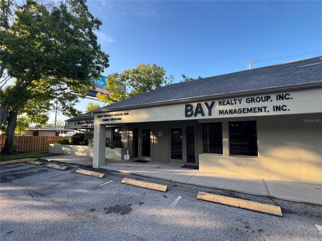 A single-story commercial building with a parking lot and signage for multiple businesses — 32502 US HIGHWAY 19 N UNIT B, PALM HARBOR, FL