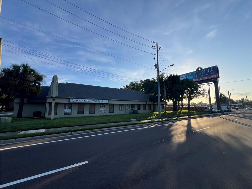 A low-rise commercial building with a gray exterior sits along a road under a blue sky — 32502 US HIGHWAY 19 N UNIT B, PALM HARBOR, FL