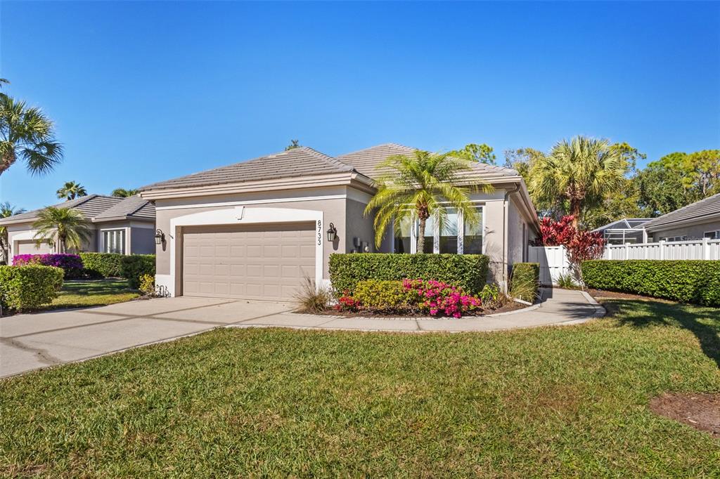 A single-story house with a beige exterior, a two-car garage, and a landscaped front yard — 8733 49TH TERRACE EAST, BRADENTON, FL