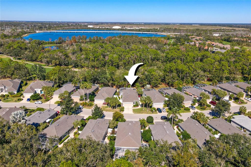 An aerial view shows a residential neighborhood with a white arrow pointing to a house — 8733 49TH TERRACE EAST, BRADENTON, FL