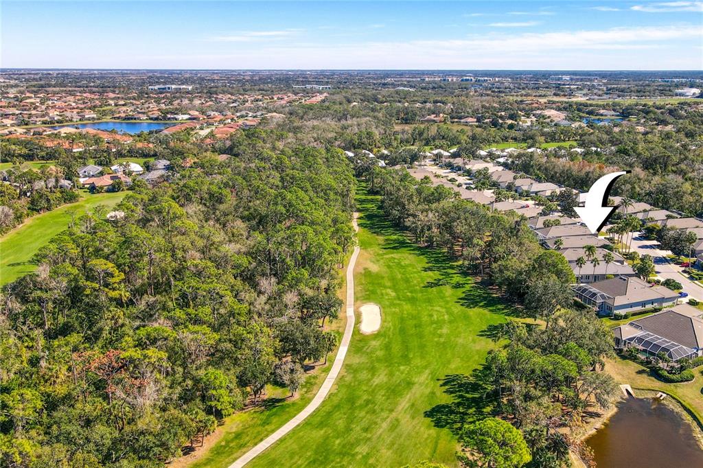 An aerial view shows a residential neighborhood bordering a golf course with a sand trap — 8733 49TH TERRACE EAST, BRADENTON, FL