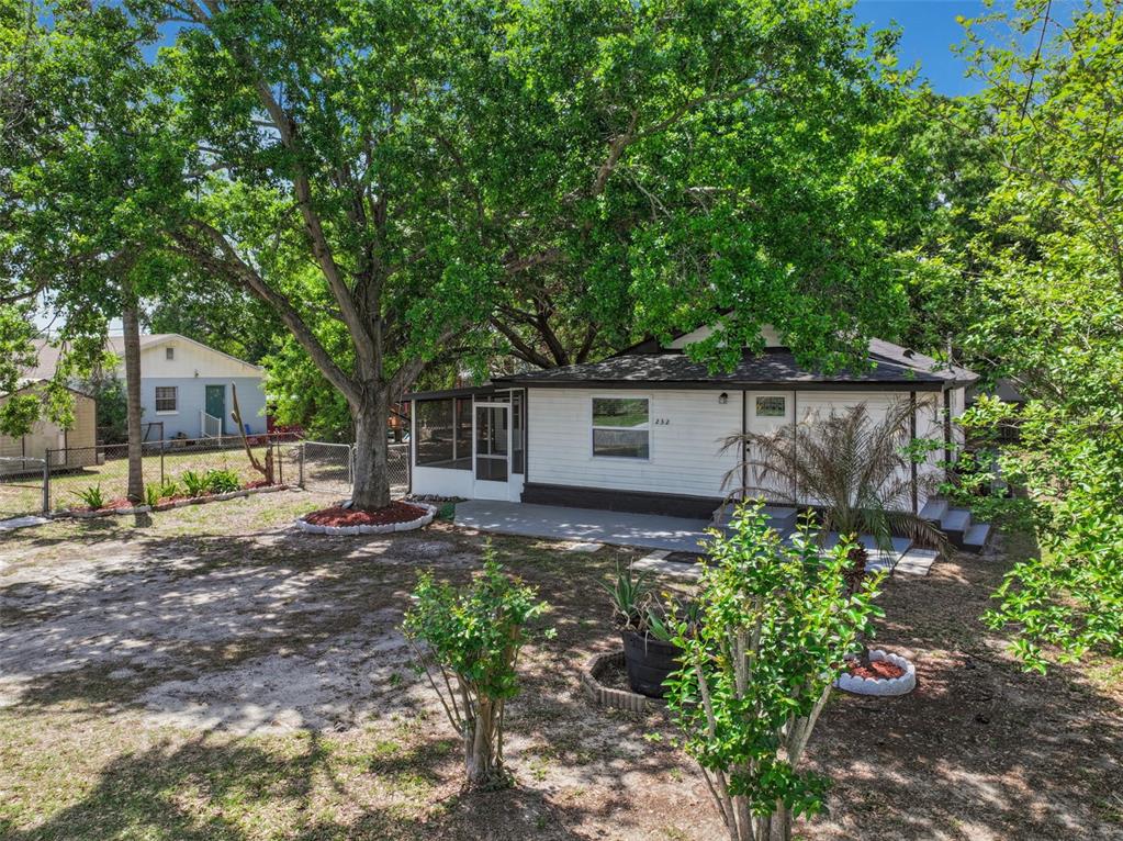 A white house with a screened porch and a large tree in the front yard — 232 NOXON STREET, AUBURNDALE, FL
