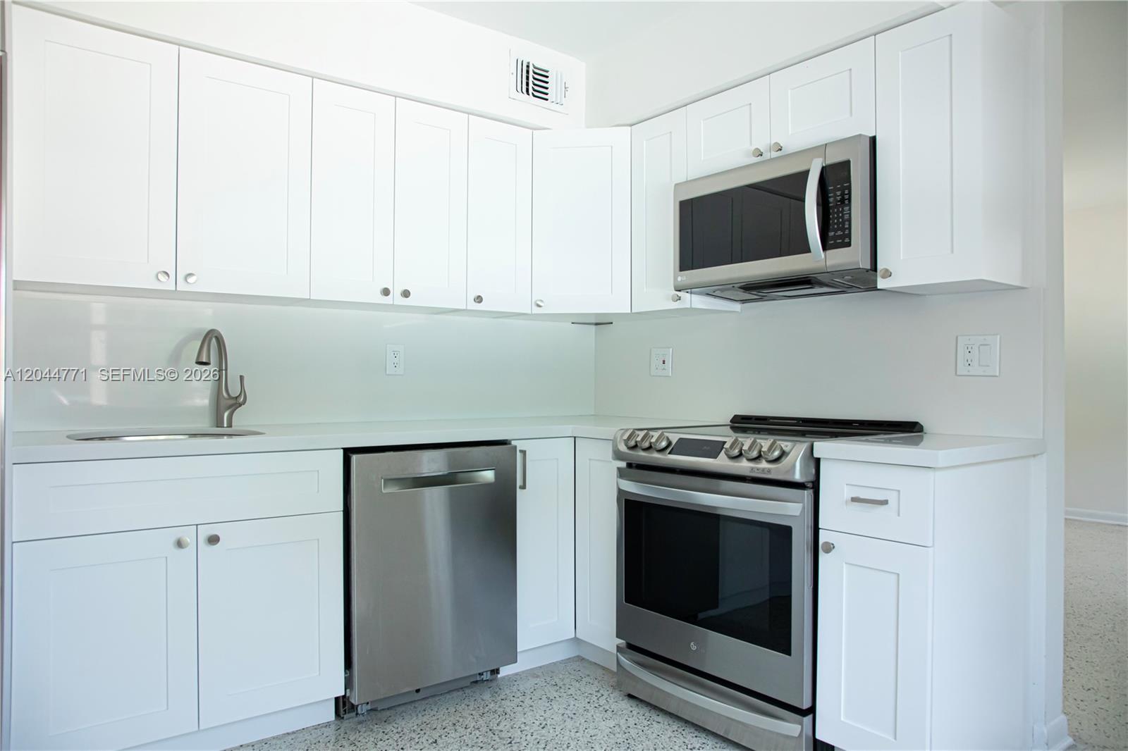 A modern kitchen features white cabinets, stainless steel appliances, and a light-colored countertop — 1226 SW 30th Ave # 1226, Miami FL 33135, MIAMI, FL