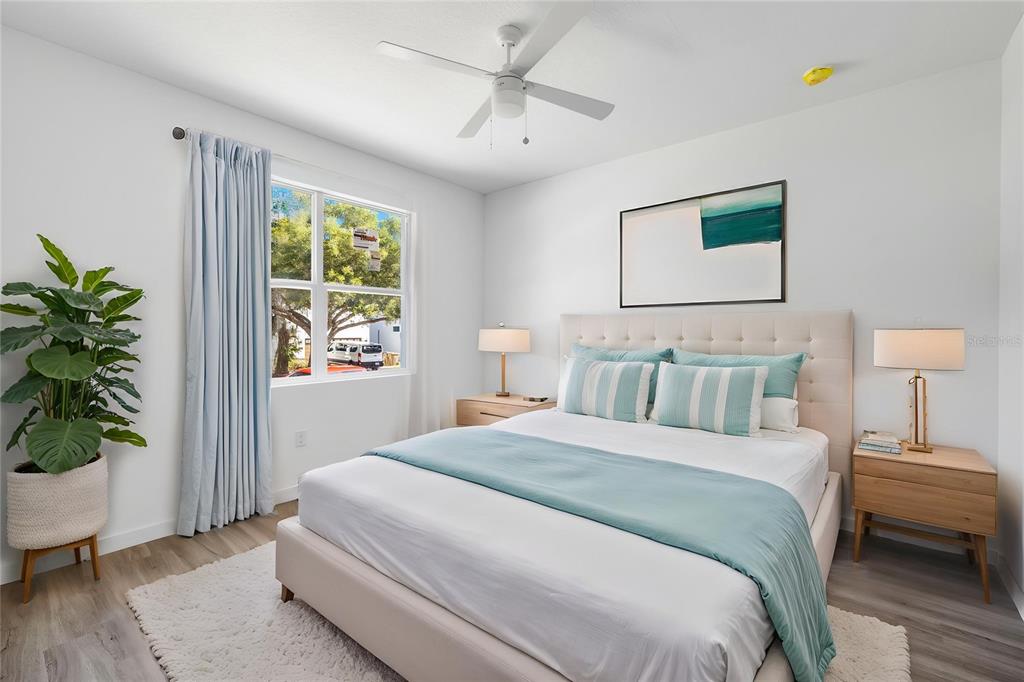 A bedroom features a bed with light blue bedding, two nightstands, and a large window — 7511 NORTHERN HARRIER WAY UNIT 102, KISSIMMEE, FL