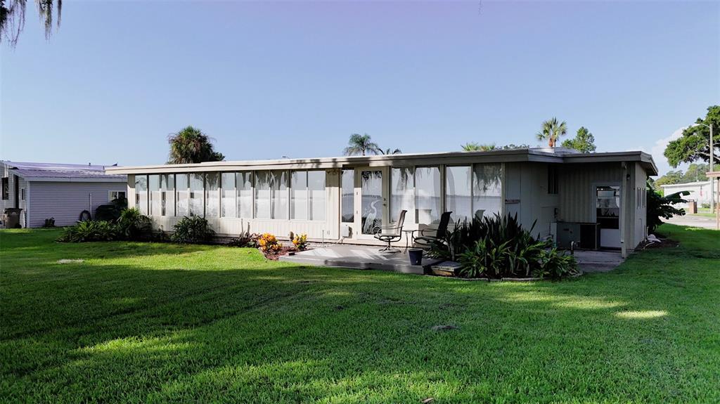 A single-story house with a large glass-enclosed sunroom sits on a grassy lawn — 34410 ISLAND DRIVE, LEESBURG, FL