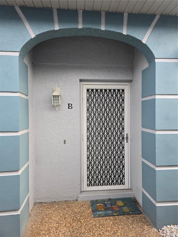 A light blue arched entryway features a white security door and a small owl-themed mat — 6551 HAMLET DRIVE UNIT B, ENGLEWOOD, FL
