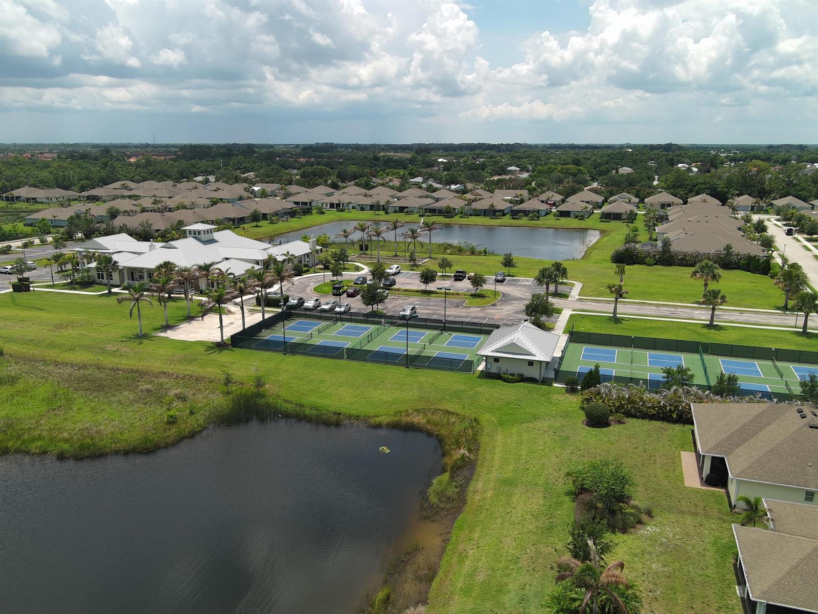 An aerial view shows a community clubhouse with tennis courts, a parking lot, and ponds — 5932 Spicewood Lane, Vero Beach FL 32966, VERO BEACH, FL