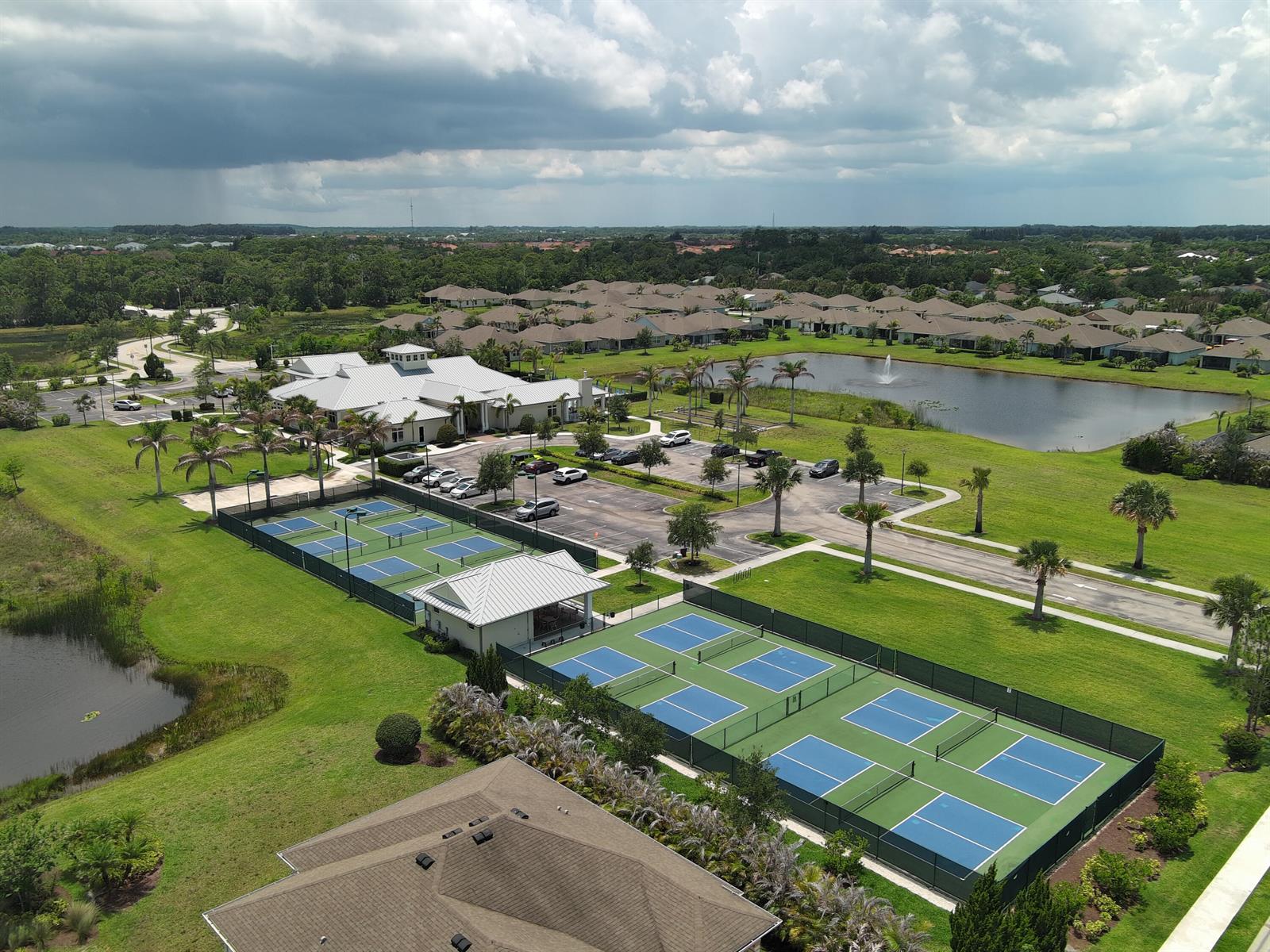 An aerial view shows a community clubhouse with tennis courts, a parking lot, and ponds — 5932 Spicewood Lane, Vero Beach FL 32966, VERO BEACH, FL