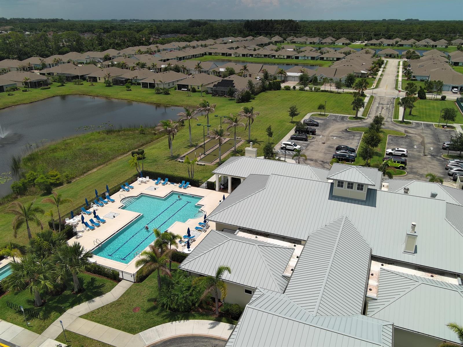 An aerial view shows a community clubhouse with a swimming pool, parking lot, and pond — 5932 Spicewood Lane, Vero Beach FL 32966, VERO BEACH, FL