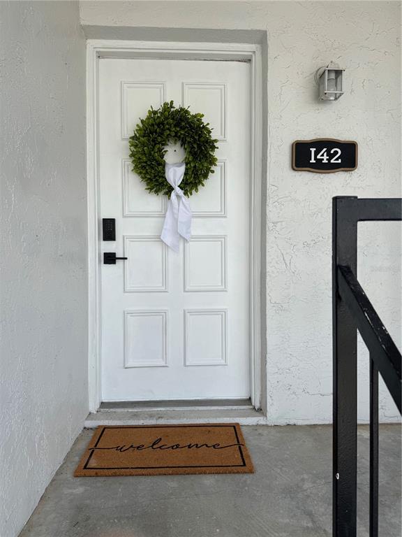 A white front door with a green wreath and a welcome mat at the entrance — 3819 N OAK DRIVE UNIT I42, TAMPA, FL