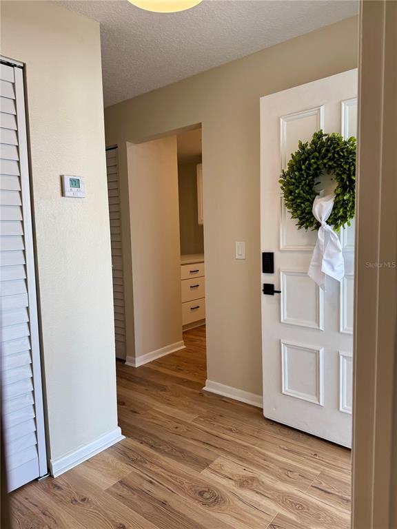 An entryway features wood-look flooring, a white door with a wreath, and a thermostat — 3819 N OAK DRIVE UNIT I42, TAMPA, FL