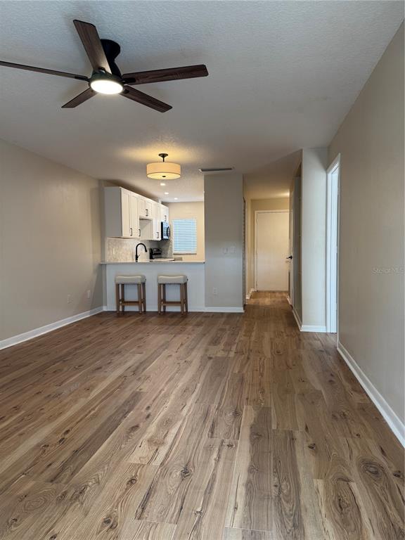 A living area with wood-look flooring leads to an open kitchen with white cabinets — 3819 N OAK DRIVE UNIT I42, TAMPA, FL