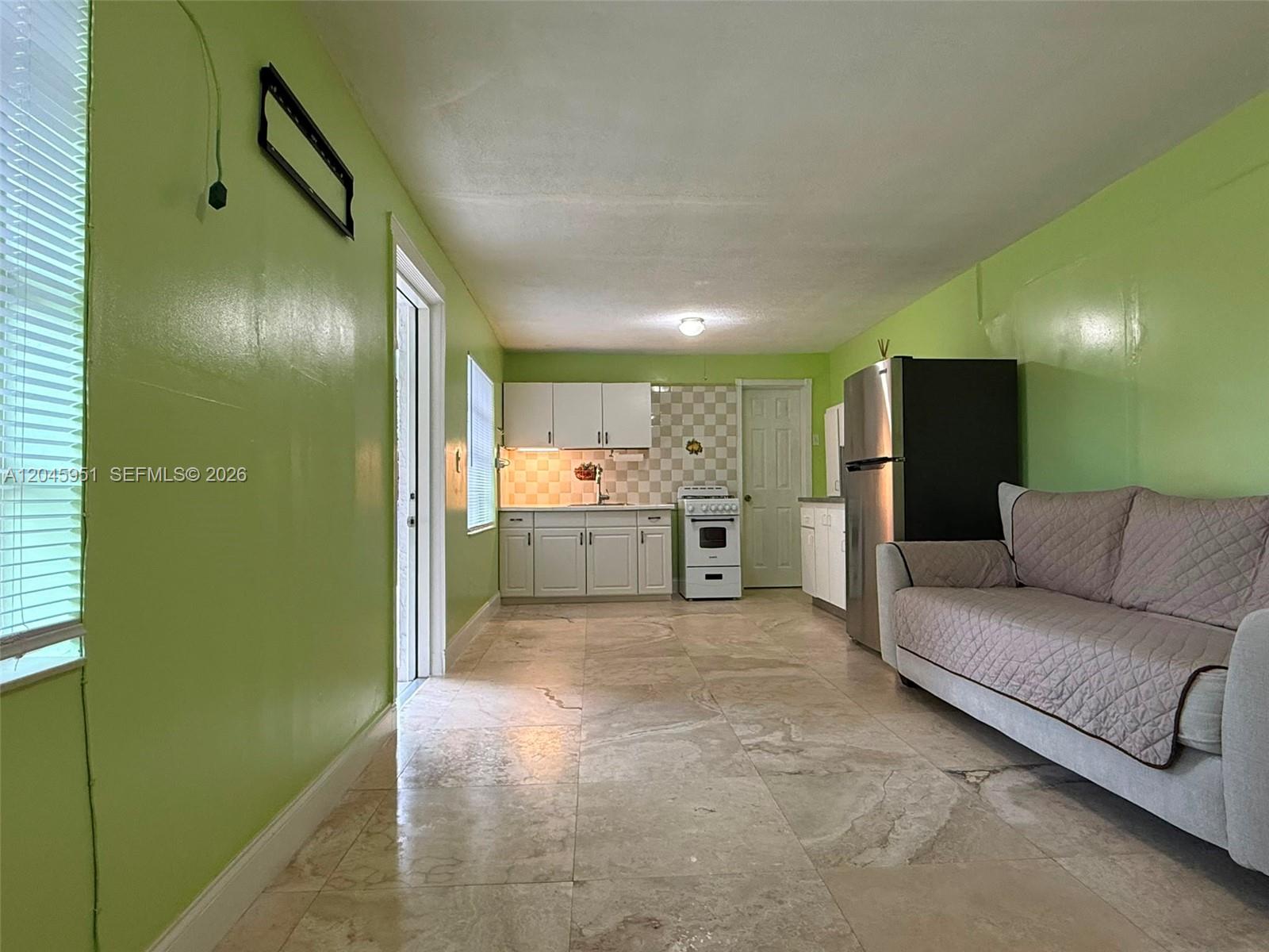 A kitchen and living area features lime green walls, white cabinets, and tiled flooring — 13330 SW 79th St, Miami FL 33183, MIAMI, FL