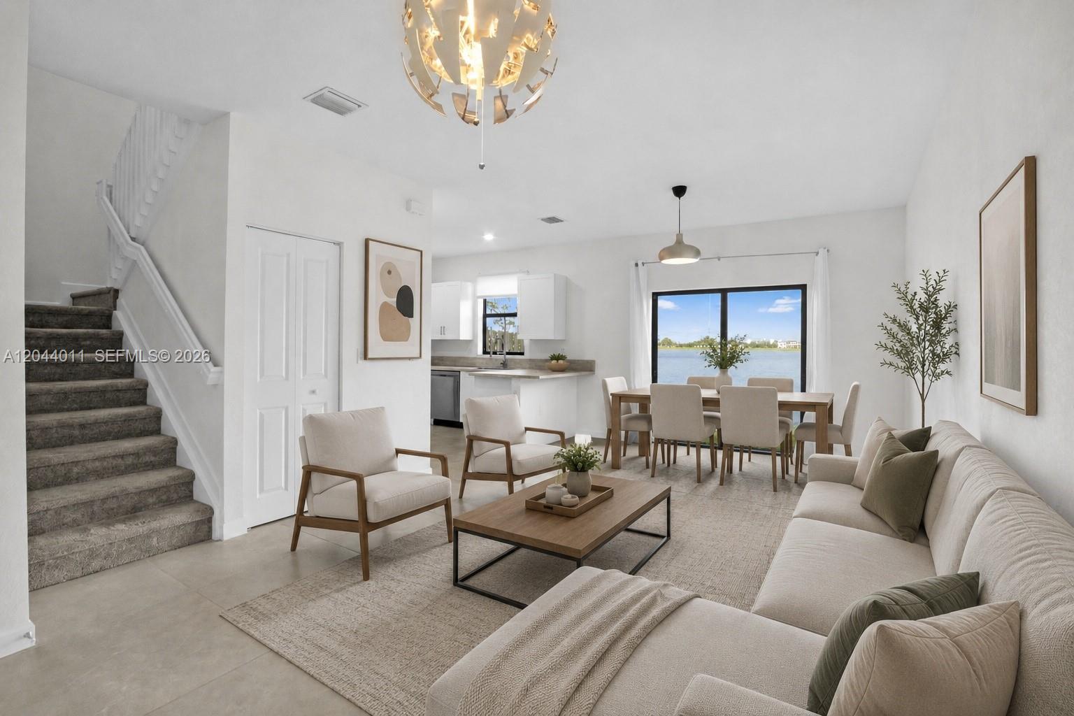 This open-concept living and dining area features neutral furniture, a staircase, and a lake view — 20610 NE 5th Pl, Miami FL 33179, MIAMI, FL