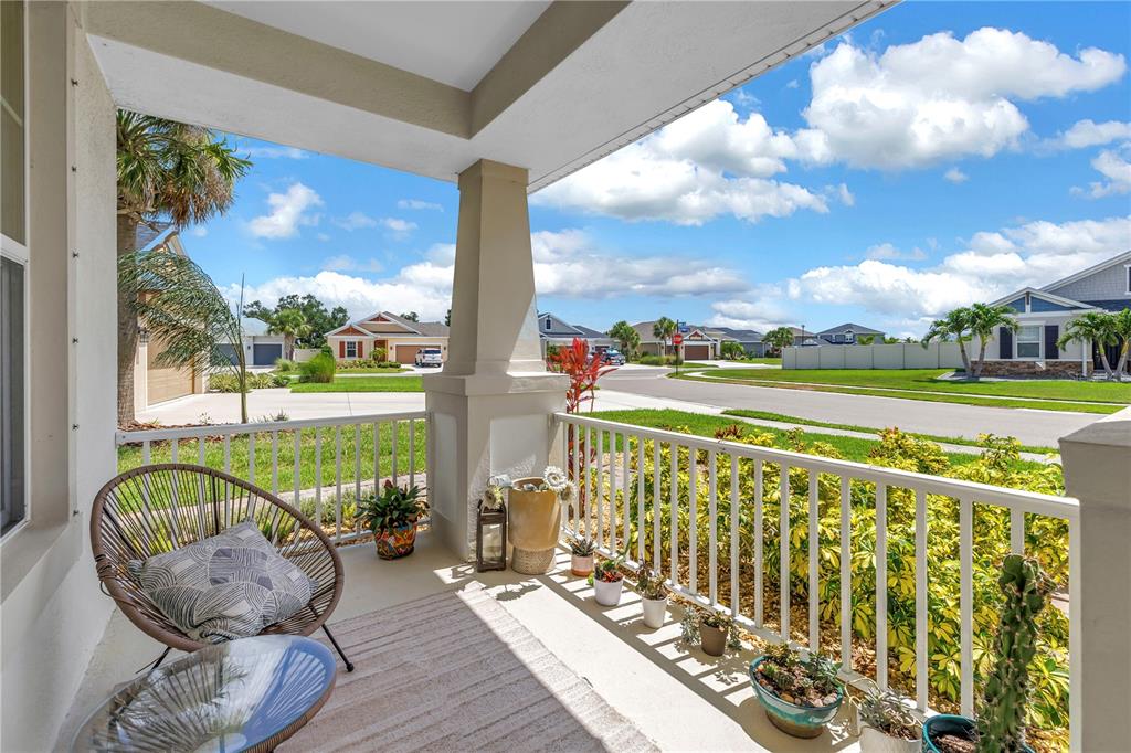 A covered front porch features a wicker chair, potted plants, and a view of the neighborhood — 10108 CORRIENTE COURT, PALMETTO, FL