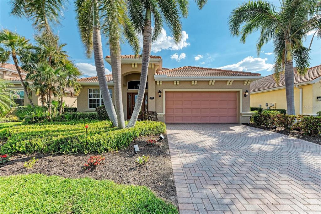 A single-story house with a paved driveway, a two-car garage, and several tall palm trees — 135 RIVER ENCLAVE COURT, BRADENTON, FL