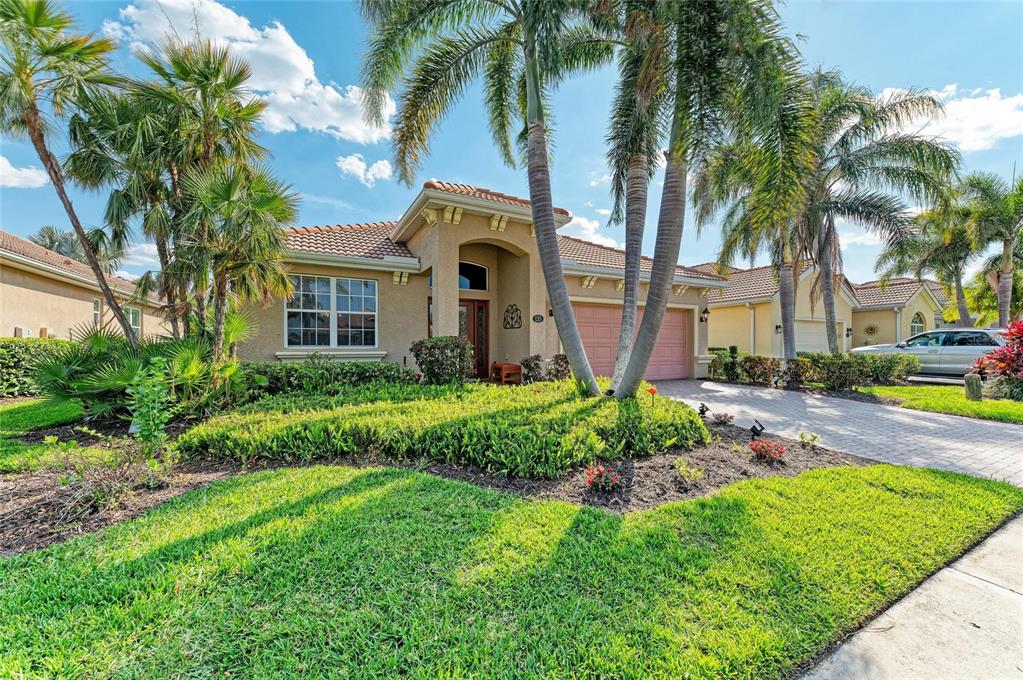 A single-story house with a tiled roof, palm trees, and a paved driveway — 135 RIVER ENCLAVE COURT, BRADENTON, FL
