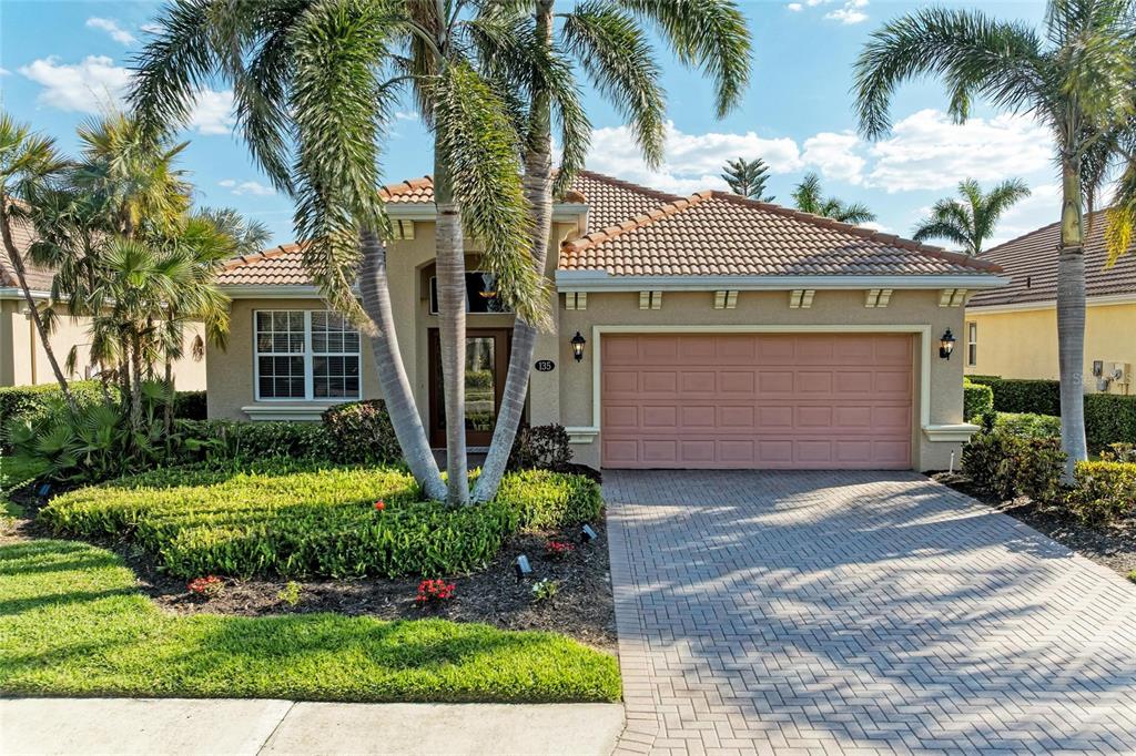 A single-story house with a tiled roof, a two-car garage, and palm trees in front — 135 RIVER ENCLAVE COURT, BRADENTON, FL