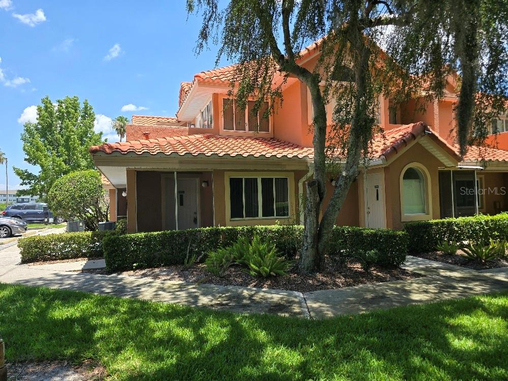 A two-story stucco townhouse with a red tile roof and a front garden area — 8302 WATERVIEW WAY UNIT 8302, WINTER HAVEN, FL