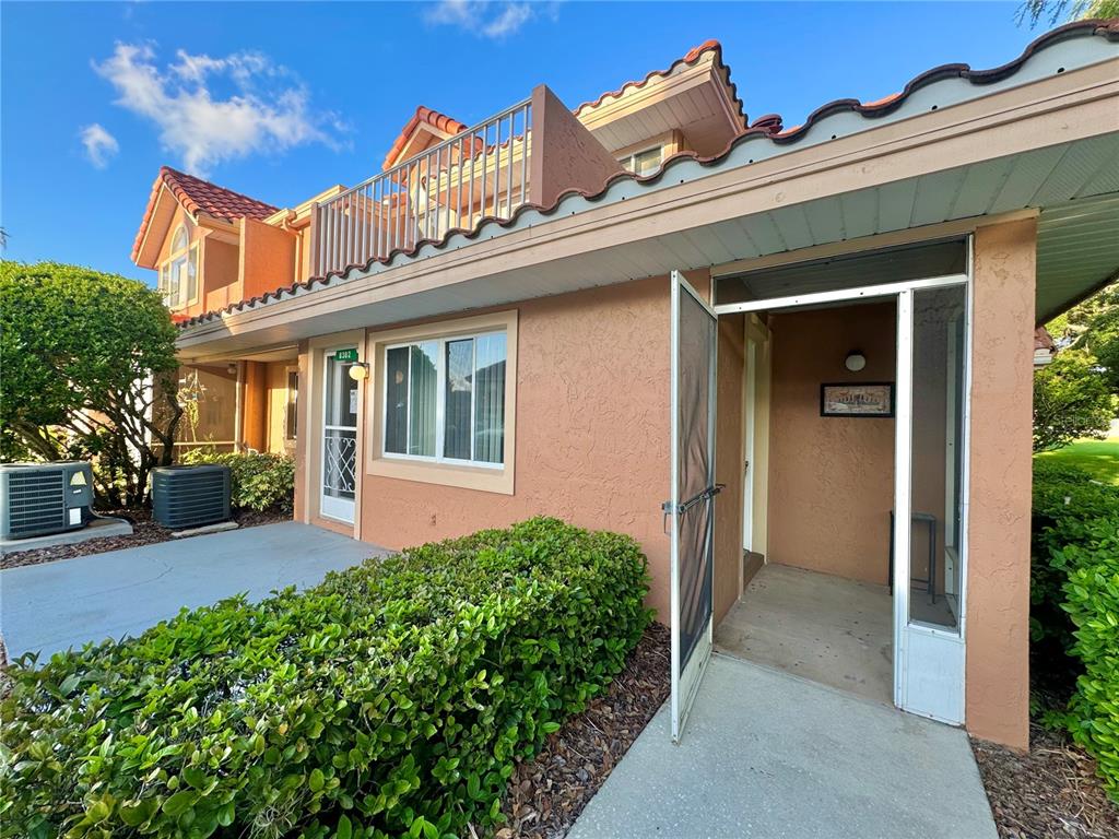 The exterior of a multi-story stucco building features a screened entryway and a balcony — 8302 WATERVIEW WAY UNIT 8302, WINTER HAVEN, FL