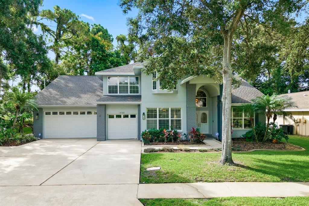 A two-story house with a three-car garage, gray siding, and a large front lawn — 4788 BRAYTON TERRACE S, PALM HARBOR, FL
