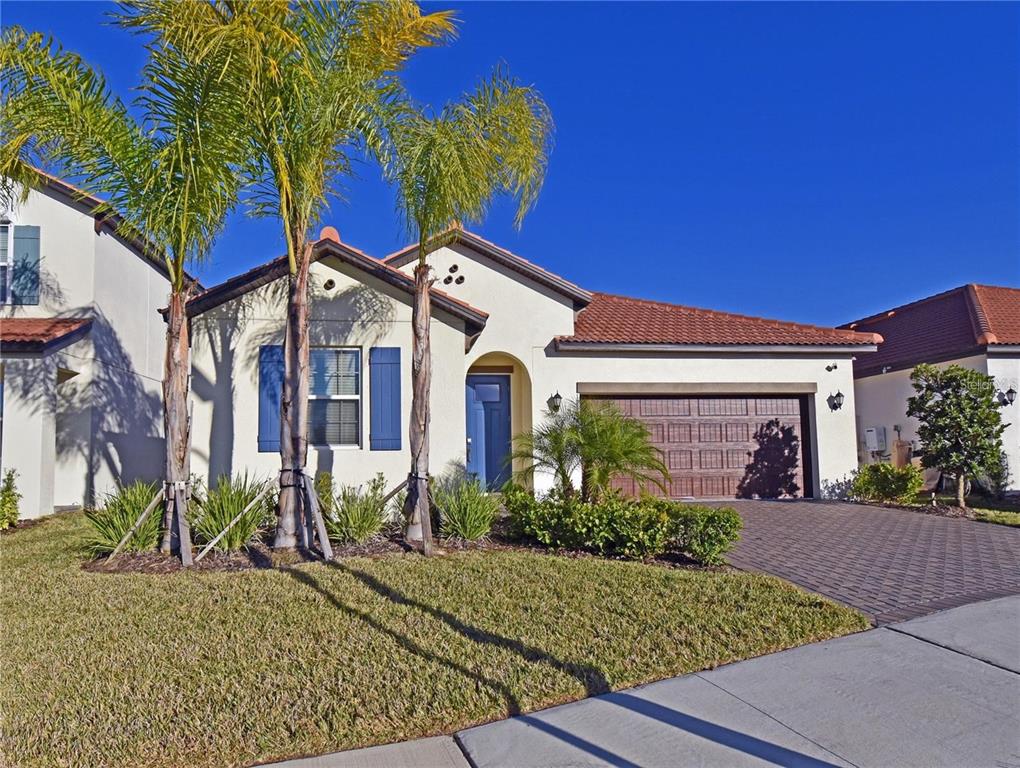 A single-story house with a tiled roof, blue shutters, and a paved driveway — 17304 BANDED GOLD LANE, WIMAUMA, FL