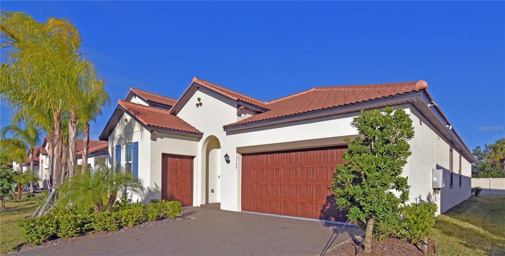 A single-story house with a white stucco exterior, a tile roof, and a three-car garage — 17304 BANDED GOLD LANE, WIMAUMA, FL