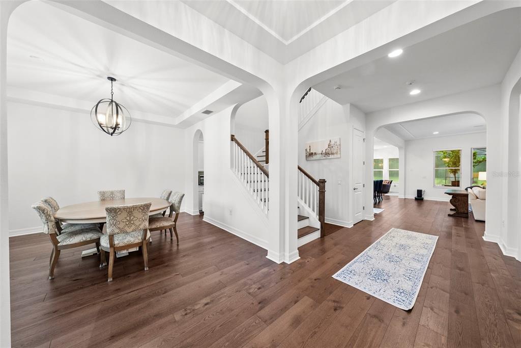 A dining area with a round table and a staircase with wooden railings and white risers — 2608 MEADOW GRANGE LANE, LUTZ, FL