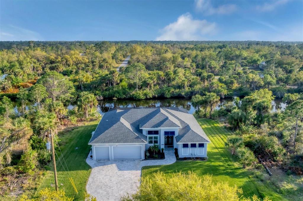 An aerial view of a single-story house with a gray roof, garage, and paved driveway — 14351 HOWARD AVE, PORT CHARLOTTE, FL
