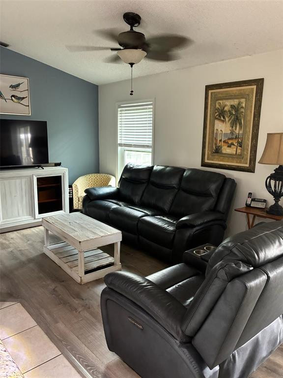 A living room features a black leather sofa, a recliner, and a white coffee table — 849 HAPPINESS AVENUE SW, PALM BAY, FL