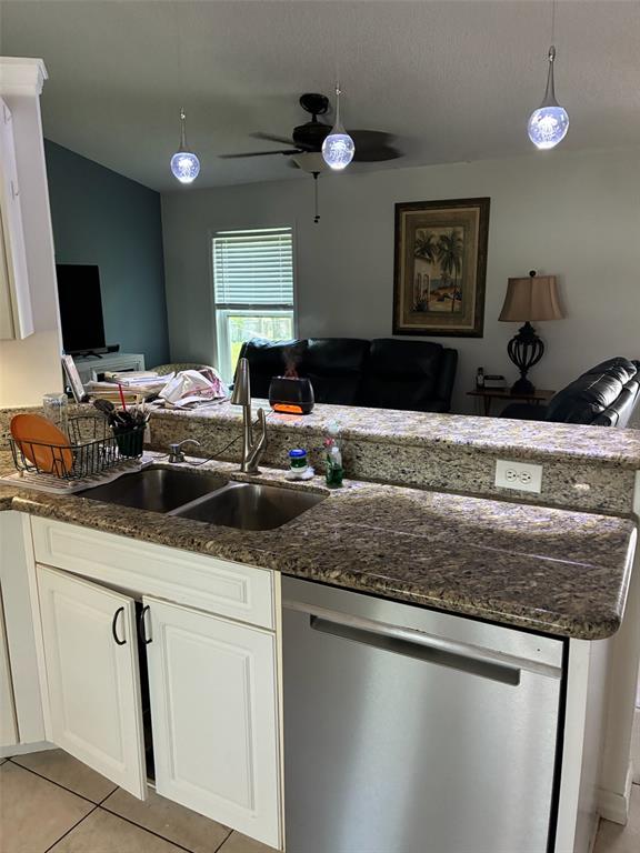 A kitchen with granite countertops and stainless steel appliances overlooks a living room area — 849 HAPPINESS AVENUE SW, PALM BAY, FL