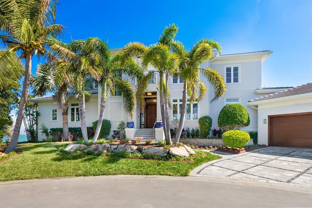 A two-story white house with palm trees, a stone landscape, and a paved driveway — 600 PUTTER LANE, LONGBOAT KEY, FL