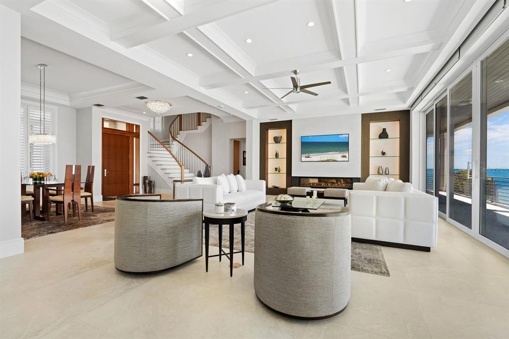 A bright, open-concept living and dining area features white furniture, a coffered ceiling, and ocean views — 600 PUTTER LANE, LONGBOAT KEY, FL