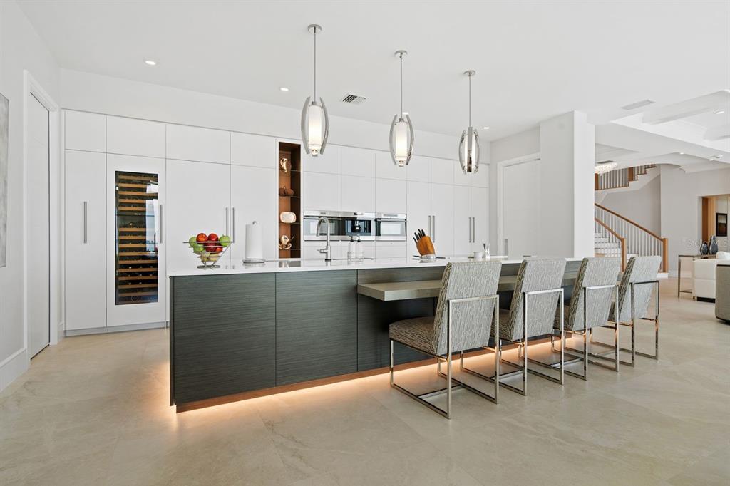 A modern kitchen features a dark wood island with bar seating and white cabinetry — 600 PUTTER LANE, LONGBOAT KEY, FL