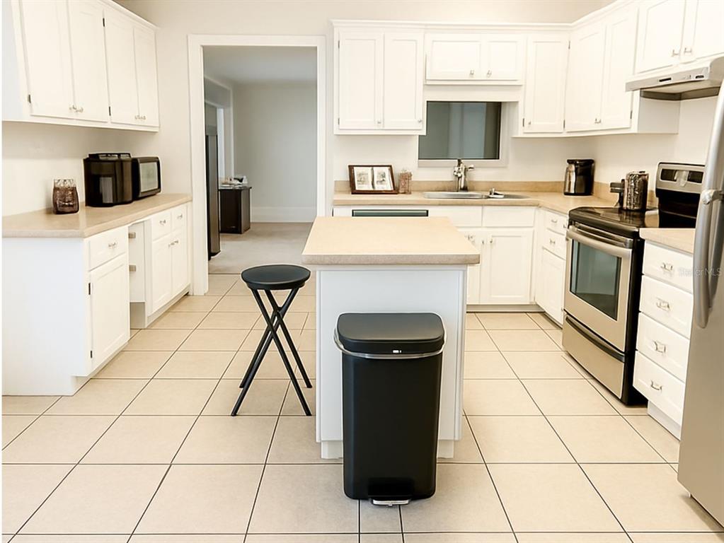 A sunlit breakfast nook features three large windows, white walls, and light-colored tiled flooring — 14640 NE 149TH LANE, FORT MC COY, FL
