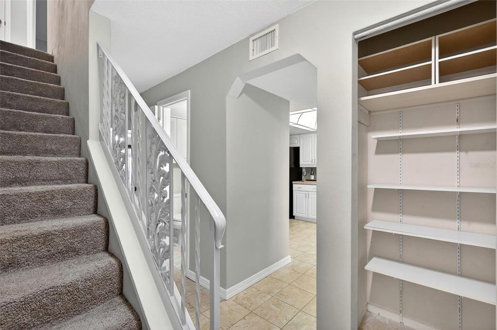 A carpeted staircase with a white metal railing sits beside a closet and a hallway — 2250 S PALMETTO AVENUE UNIT J-5, SOUTH DAYTONA, FL