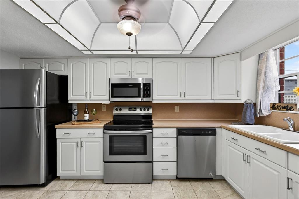 A kitchen features white cabinets, stainless steel appliances, a tan countertop, and a tray ceiling — 2250 S PALMETTO AVENUE UNIT J-5, SOUTH DAYTONA, FL