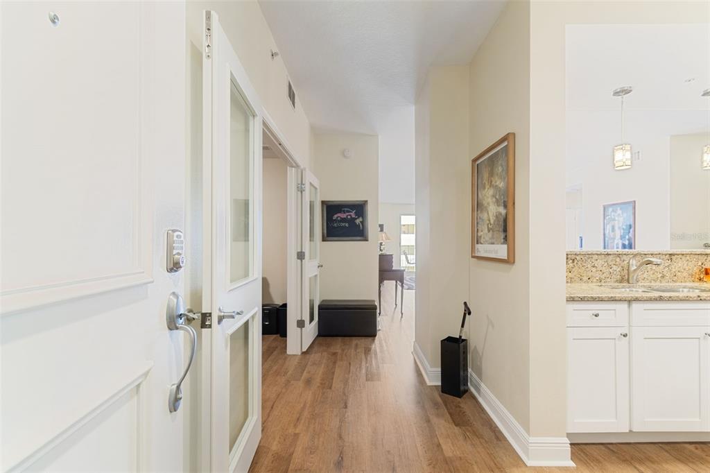 A hallway with wood-look flooring leads to an open living area past a kitchen counter — 628 CLEVELAND STREET UNIT 904, CLEARWATER, FL