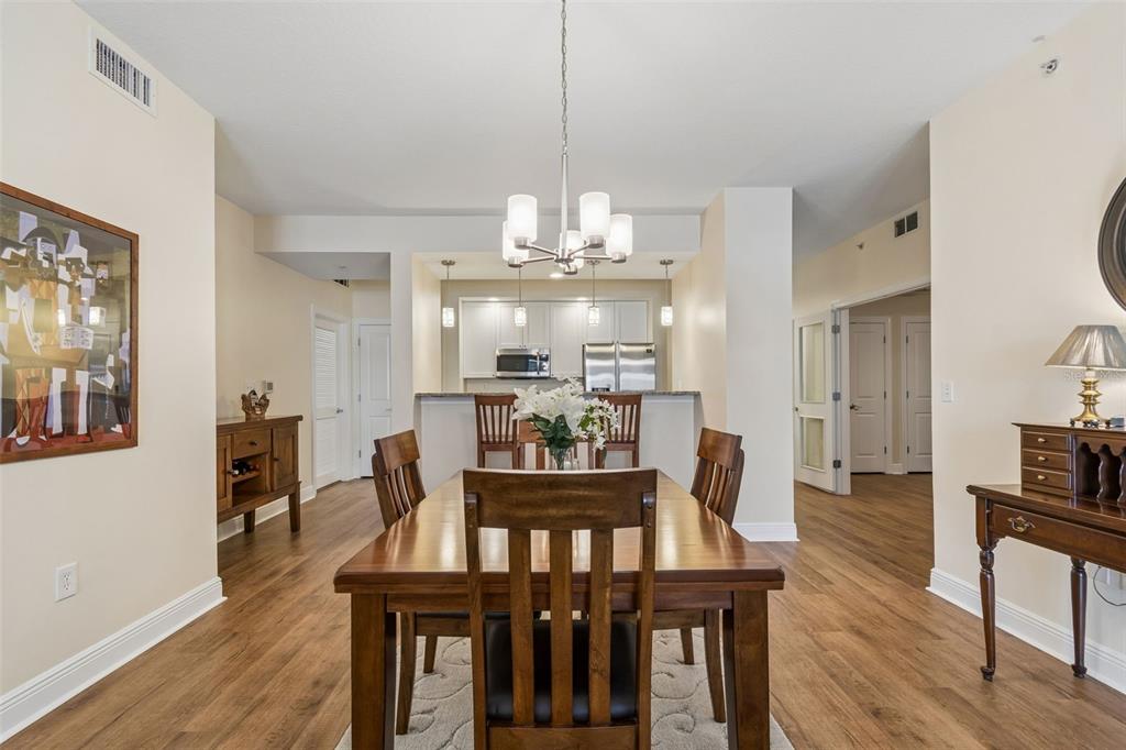 A dining area with a wooden table and chairs sits in front of an open kitchen — 628 CLEVELAND STREET UNIT 904, CLEARWATER, FL