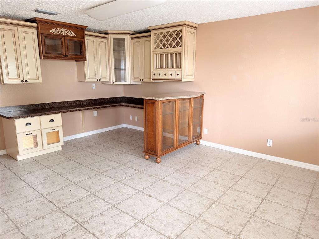 A kitchen area features light-colored cabinets, a dark countertop, and a wooden glass-fronted peninsula — 2914-A KENILWORTH BOULEVARD, SEBRING, FL