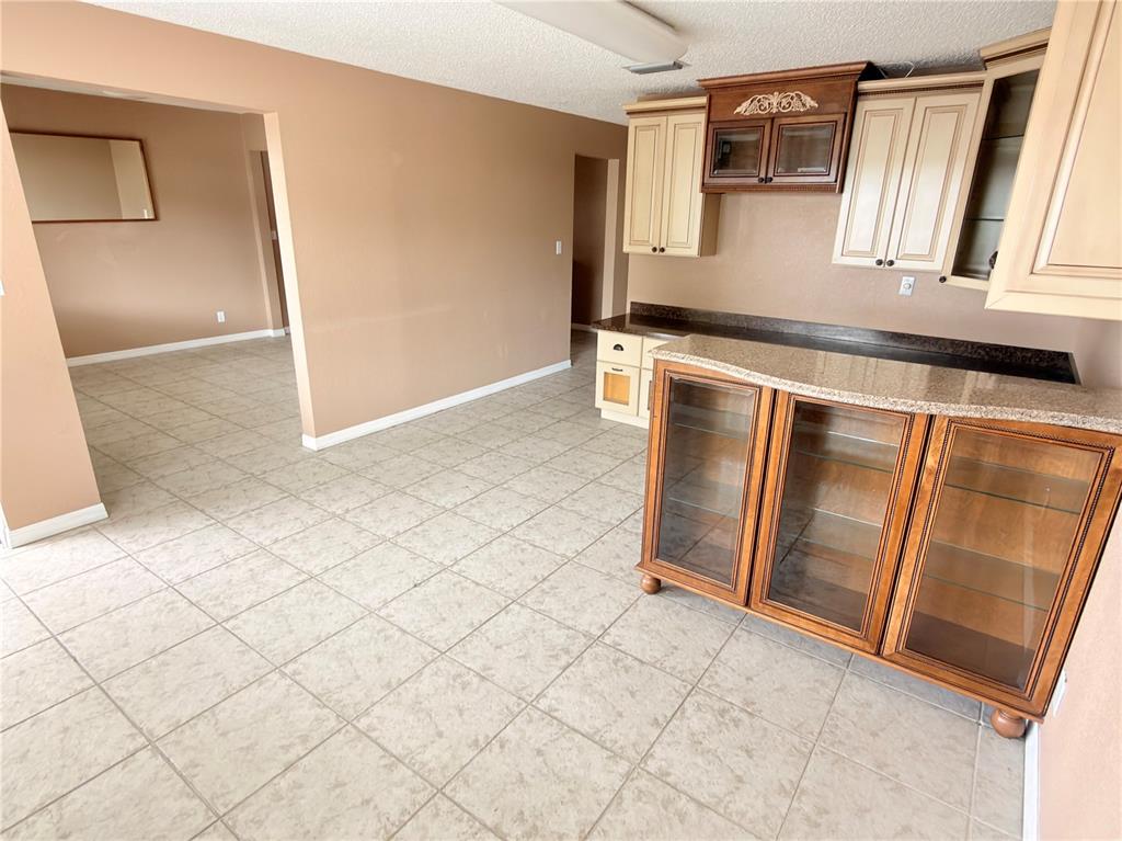 A kitchen area features tile flooring, granite countertops, and a mix of wood and cream cabinetry — 2914-A KENILWORTH BOULEVARD, SEBRING, FL